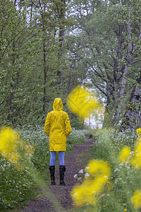 春生带黄雨衣和橡胶靴的年轻女青年天气公园衣服裙子女士季节女性下雨雨鞋橡皮背景图片