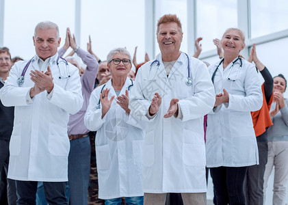 医生和一群成熟的病人鼓掌欢呼专家男人团队女士职员诊所医院长袍职业男性背景图片