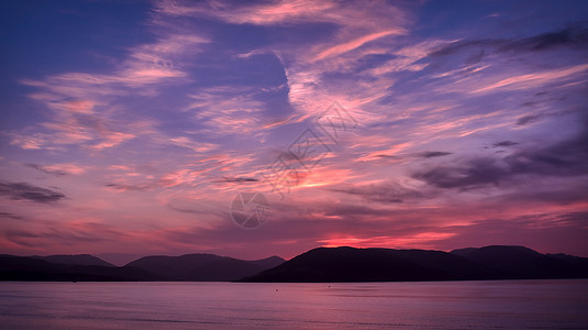 红蓝天空日落多彩 红蓝的天空 在河流和山丘之上背景