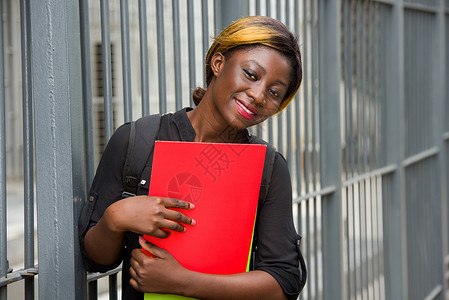 年轻的学生肖像带文件 微笑着手指女士编织背包校园图书女性姿势大学化妆品背景图片