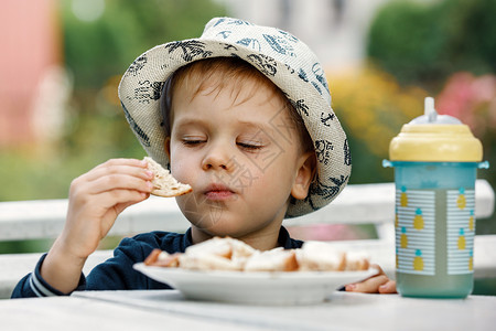 可爱的小孩在户外绿色花园里吃面包的特写肖像 夏季生活方式 自产有机食品 健康的儿童营养乐趣高清图片素材