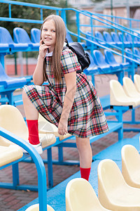 穿黄裙子女孩学校体育场蓝黄相间的看台上穿着校服的漂亮女孩 上学时间 吐温蓝色椅子发型女性活动青少年休闲装头发潮人青年背景