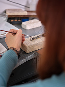 一名在手工首饰车间工作的妇女 她用戒指上的小刷子在一块石块上做工工匠精神高清图片素材