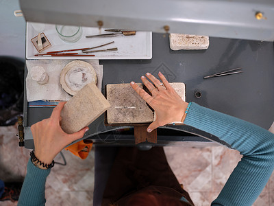 一位成年女性在她的工匠珠宝作坊工作 她坐在工作台前使用石块进行工作成人高清图片素材