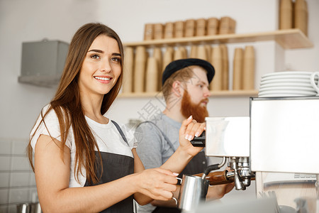 咖啡业务概念站在咖啡馆时 女咖啡师穿着围裙准备和蒸牛奶 与她的伴侣一起点咖啡餐厅机器投手职业女士棍棒男性工作服务员咖啡店热的高清图片素材
