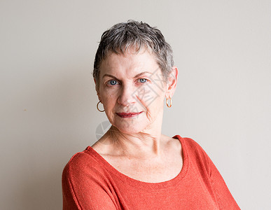 短灰头发和橙色顶部的老年妇女肖像背景图片