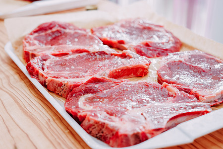 在烹饪课上煮牛排的老牛肉 生牛肉和绿菜 特制香料屠夫食物宏观餐厅桌子肋骨奶牛眼睛厨房背景图片