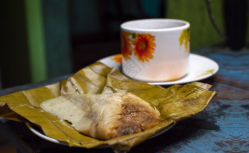 木制餐桌 香蕉叶上塞满的塔马人 木制餐桌 典型的尼卡拉瓜食品食物玉米美食烹饪叶子盘子面包早餐蒸肉背景图片