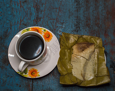 木桌上放着玉米粉蒸肉 香蕉叶上放着玉米粉蒸肉 木桌上放着一杯咖啡 这是典型的尼加拉瓜食物早餐美食玉米食品叶子面包蒸肉盘子烹饪背景图片