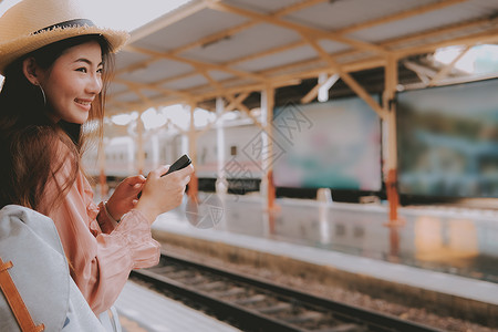 手机背贴素材背包里的女旅客在火车站使用智能手机 旅行旅行旅行概念游客铁路火车民众运输互联网女性乘客车站技术背景