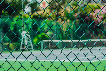 现代时尚酒店空荡荡的网球场 裁判塔 透过金属网围栏观看 明亮清新的热带绿色 体育乐趣暑假生活方式活动户外晴天背景图片