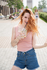 带着牙套的年轻红发美女 夏天喝着冷却鸡尾酒 在户外凉快 夏日 一个微笑的女孩的肖像与雀斑背景图片