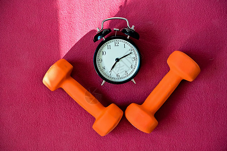 两条橙色隧道和一张粉红色瑜伽垫上的闹钟 该用设备在家健身了 检疫体育纪律力量减肥健身房警报腹肌工具培训师瑜伽重量身体背景图片