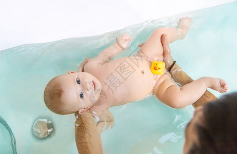 父亲给小宝宝洗澡 有选择地集中注意力童年保健妈妈生活女孩身体浴缸母亲浴室儿子干净的高清图片素材