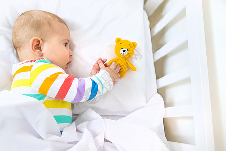 婴儿床里的婴儿上床睡觉 有选择地集中注意力女士童年男生毯子母性玩具卧室婴儿床微笑女孩背景
