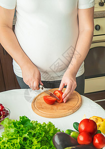 孕妇吃蔬菜和水果 有选择性地集中注意力父母女孩厨房腹部婴儿饮食肚子营养女性母亲健康高清图片素材
