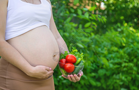 孕妇手里拿着蔬菜 有选择的专注点营养母性沙拉食物母亲女孩厨房腹部福利女士快乐的高清图片素材