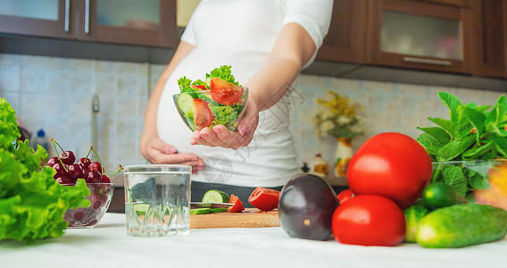 孕妇吃蔬菜和水果 有选择性地集中注意力怀孕腹部母亲厨房素食主义者沙拉成人母性女士父母饥饿的高清图片素材