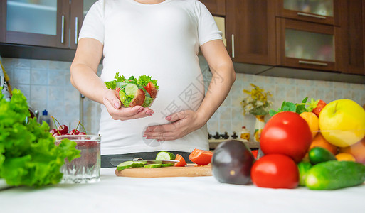 孕妇吃蔬菜和水果 有选择性地集中注意力腹部沙拉营养怀孕父母饮食女孩厨房婴儿女士美丽的高清图片素材