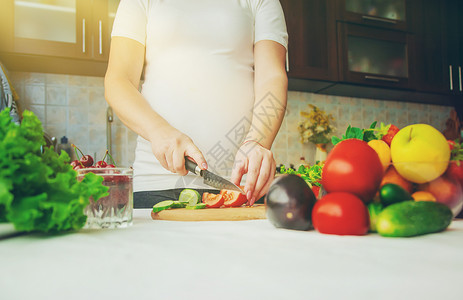 孕妇吃蔬菜和水果 有选择性地集中注意力女孩父母饮食母亲肚子沙拉厨房母性营养成人家高清图片素材