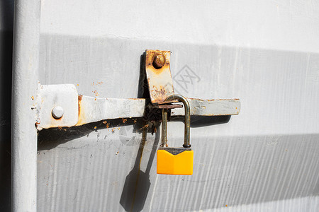 灰金属门上的黄锁工厂隐私古董房子机器监狱栅栏力量挂锁入口背景图片