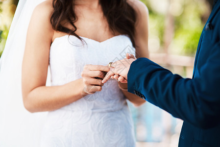 有了这件事 我发誓永远爱你 在婚礼当天站在户外时 一位面目全非的新娘将戒指套在新郎手指上的短镜头背景图片