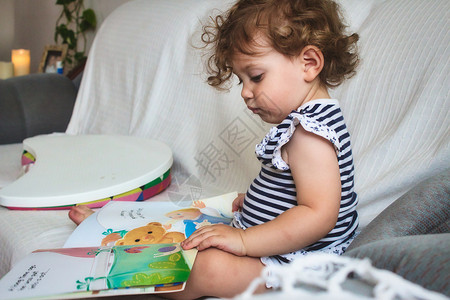 小女孩在白色沙发上读画的书教育女孩阅读故事页数房子评书孩子学习插图背景图片