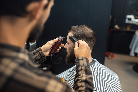 理发店主用剪发机给男人理发剪子胡须理发师成人沙龙治疗程式化男性商业剃刀滑动式高清图片素材