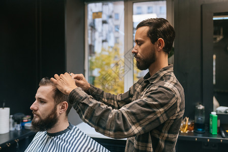 快乐的留着胡子的年轻男子在理发店被理发师理发发型男性客户梳子职业男人沙龙治疗工作美容店铺高清图片素材