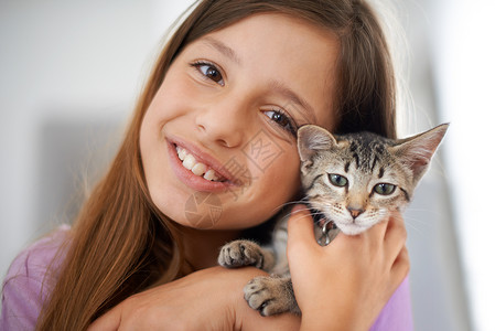 抱宠物的小姑娘一个快乐的年轻女孩 抱着一只小猫很亲切背景