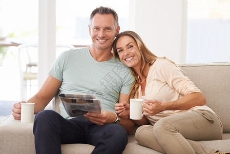 分享晨报 一对幸福的已婚夫妇在沙发上看报纸的肖像高清图片