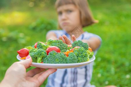 领胡萝卜女孩儿童吃蔬菜花椰菜和胡萝卜 有选择性的焦点孩子们桌子沙拉花园女孩童年营养围裙厨房眼镜背景