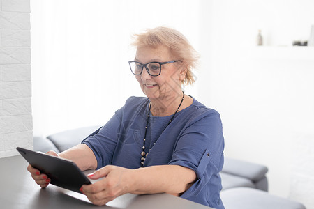 快乐成熟的中年女性在家里使用数字平板电脑度过闲暇时光 性格开朗的现代高级女士拿着电脑 看有趣的电影和笑声 休闲和科技理念购物摄像互联网高清图片素材