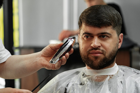 理发师给在理发店坐在椅子上 长胡子的男人理发胡须客户顾客发型店铺头发工具潮人男性造型师微调器高清图片素材