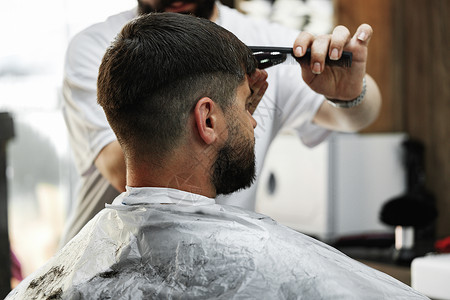 理发师给在理发店坐在椅子上 长胡子的男人理发头发商业客户成人职业顾客服务男性沙龙发型微调器高清图片素材