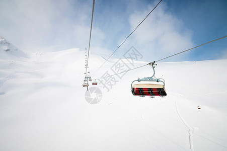高山顶的露天升空 下坡滑雪 日落之日被雪田包围 天气好时滑雪度假村斜坡高度运动山脉旅行蓝色滑雪者电缆缆车升降椅滑雪板背景图片