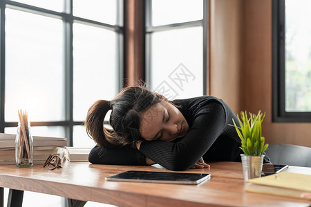 疲惫 压力重重的亚洲年轻女商务人士工作 摘下眼睛疲劳眼镜 小睡 在使用笔记本电脑时努力工作后睡在办公桌上 办公室综合症 加班 累商业高清图片素材