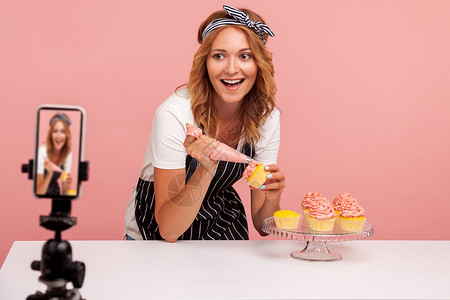 厨师大赛现场以粉红色背景为年轻女性做室内烹饪蛋糕互联网甜点美食喜悦社交饼干网络围裙电话背景