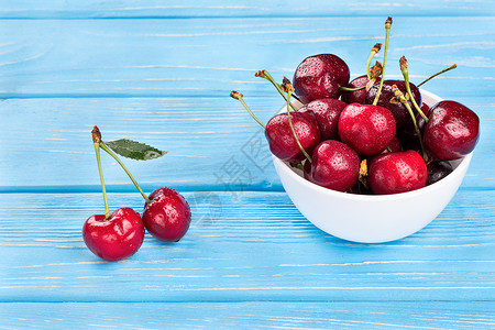 碗中的红樱桃蓝色食物红色桌子白色团体叶子水果木头浆果健康高清图片素材