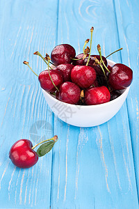 碗中的红樱桃木头浆果团体叶子水果食物红色桌子蓝色白色红色的高清图片素材