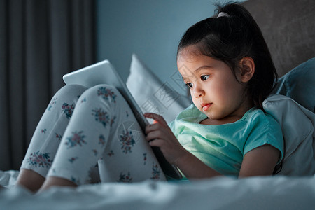是时候说晚安了 一个小女孩躺在床上时 使用数字平板电脑的小孩背景图片