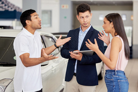 选择汽车从来都不是一个容易的决定 一对年轻夫妇在汽车推销员面前发生争执背景图片
