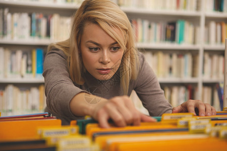 在图书馆学习的有魅力的女人学生学校顾客中学项目家庭作业店铺民众购物图书背景图片