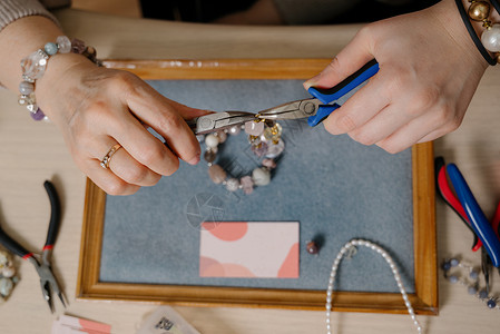 蓝色珠宝框架珠宝制作和珠蜜过程 时尚 创造力和手工创作概念器具设计师工艺生产作坊项链玻璃礼物剪刀珍珠背景