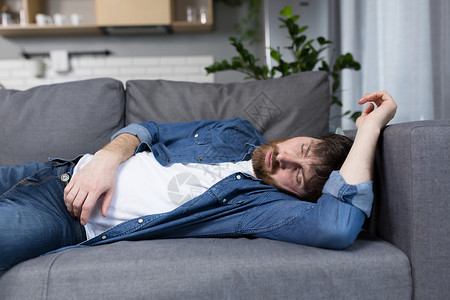 一个在家工作后在沙发上睡觉的男子午睡房间商业商务压力休息失眠男性人士说谎无聊高清图片素材
