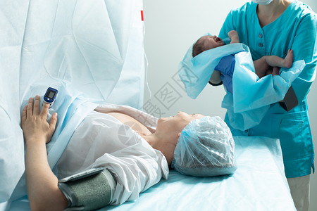 护士在医院里将新生儿与母亲亲近的婴儿抱在一起外科脉冲手术送货妈妈劳动男生切口孩子分娩药品高清图片素材