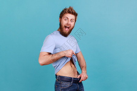 穿蓝色T恤的男人 穿着长裤的瘦腰有意志力点 成功地减肥背景图片