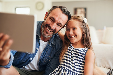 一个可爱的小女孩 在家里用数字平板电脑和父亲一起自拍 她很聪明 她喜欢听那些小屁孩背景图片