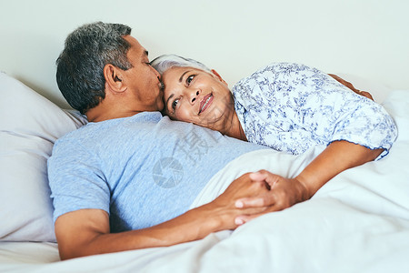 让我们今天什么都不做 一对放松的成熟夫妇在早上一起躺在家里的床上背景图片