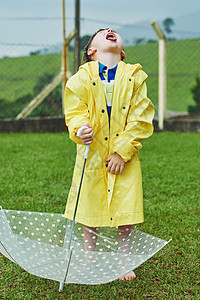 撑着雨伞孩子是时候喝点雨水了 下雨天 一个开朗的小男孩撑着雨伞站在外面张嘴接雨背景